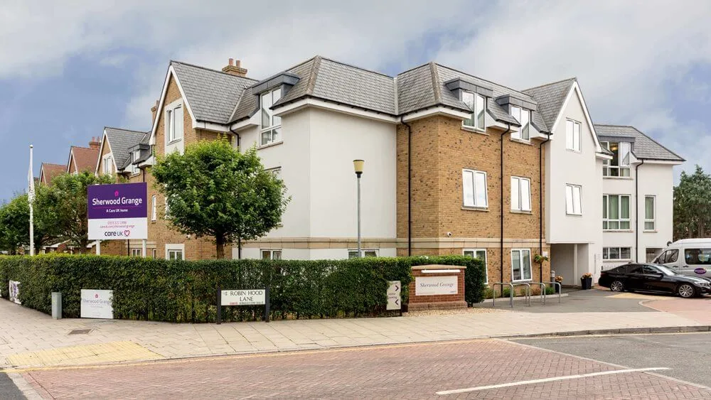The brick and white-rendered front of Sherwood Grange care home, with a Sherwood Grange sign by the hedge on Robin Hood Lane